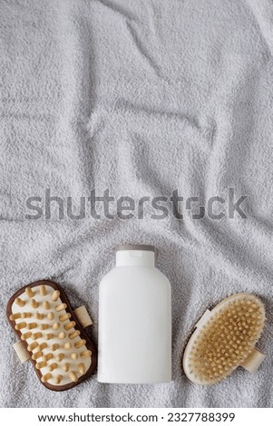 Top view of cream and massage brush on grey towel with copyspace