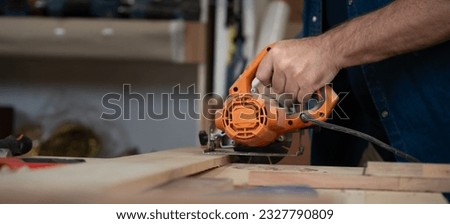 Male carpenter working with skill in carpentry workshop. Professional joiner works with power tools in woodworking. Close up of mature woodworker making or repairing furniture. Craftsmanship industry Royalty-Free Stock Photo #2327790809