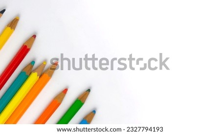 Children's colored pencils dropped on a white sheet diagonally to the left of the image, photo for back to school with space for texts, without background