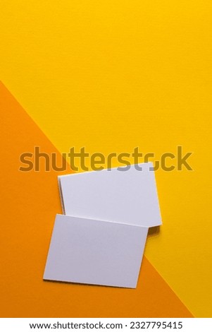 Vertical image of white business cards with copy space on yellow and orange background. Business, business card, stationery and writing space concept.