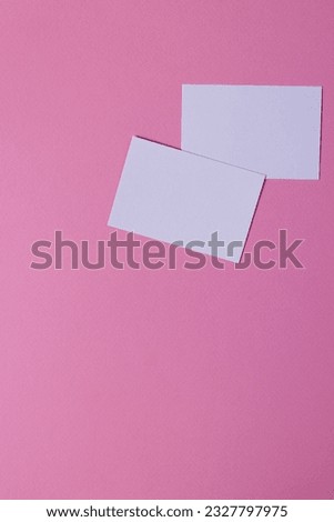 Vertical image of white business cards with copy space on pink background. Business, business card, stationery and writing space concept.