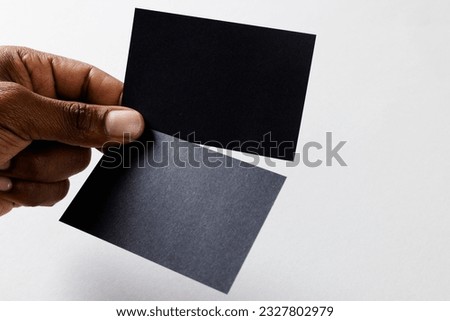 Hand of biracial man holding black business cards with copy space on white background. Business, business card, stationery and writing space concept.