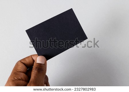 Hand of biracial man holding black business card with copy space on white background. Business, business card, stationery and writing space concept.