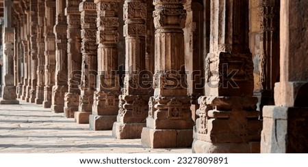 Stone columns with decorative bas relief of Qutb complex in South Delhi, India, close up pillars in ancient ruins of mosque landmark, popular touristic spot in New Delhi, ancient indian architecture Royalty-Free Stock Photo #2327809891