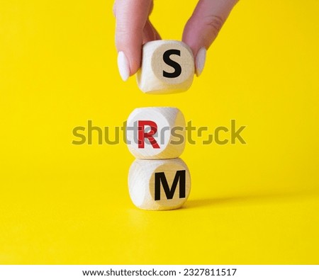 SRM - Sustainability Risk Management symbol. Wooden cubes with word SRM. Businessman hand. Beautiful yellow background. Business and Finace and SRM concept. Copy space.