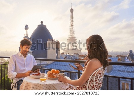 Travel, breakfast and couple in Paris with the Eiffel Tower on a terrace for romance or anniversary. City, vacation or tourism tech app with a man and woman eating food while looking at a view Royalty-Free Stock Photo #2327818725