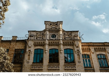 Facade of an old brick building with a tower. Building against the sky. Beautiful old architecture. University park. Tourist place of Kyiv. Gothic architecture.