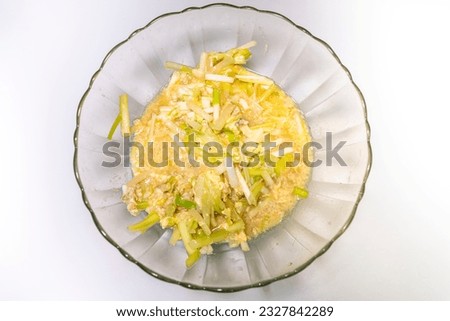 High angle view of fried eggs with leek yellow in a transparent glass bowl on a white background