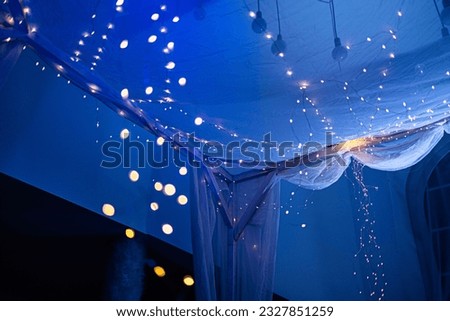 A garland that decorates a double bed. Intimate and festive atmosphere. Blue background light fill.