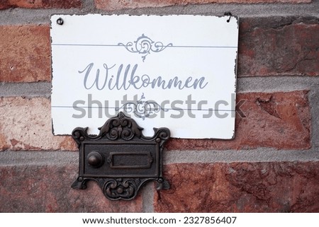 A decorative sign with the inscription Welcome and a retro-style doorbell