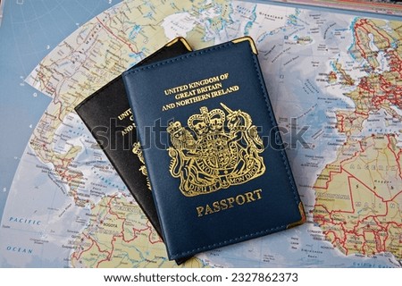 
Two British passports overlapping on a map of the world Royalty-Free Stock Photo #2327862373