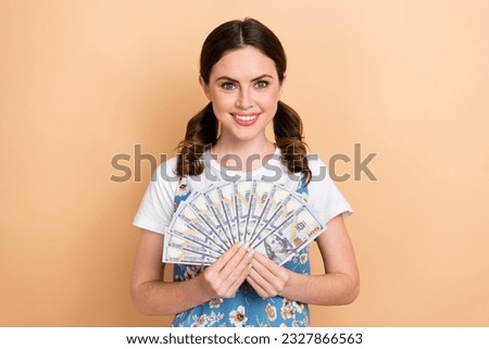 Photo of shiny adorable lady wear flower print dress holding money cash fan isolated beige color background