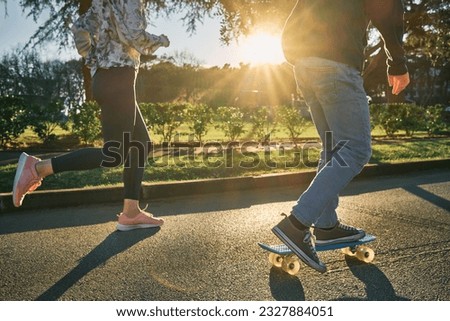 Happy family outdoors, mother and son running, go in sports, Boy rides skateboard, mom runs on sunny day. Silhouette people at sunset. Health care, authenticity, sense of balance and calmness.