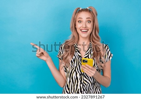 Photo of charming astonished person hold smart phone indicate finger empty space promo isolated on blue color background