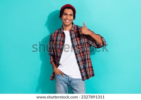 Photo portrait of nice young guy showing thumb up good quality dressed stylish checkered clothes isolated on cyan color background