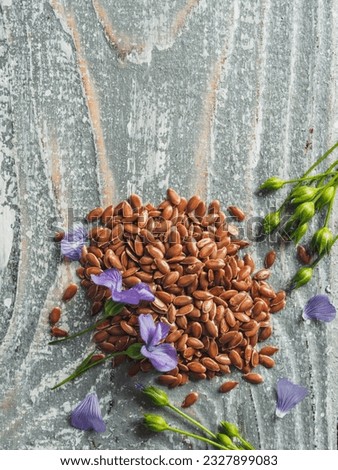 Flax seeds and flax oil. Brown linen seeds, flaxseed oil and blue flax flowers on old gray wooden background. Copy space. Vertical. Top view or flat lay. Royalty-Free Stock Photo #2327899083