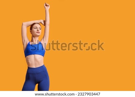 Young woman wearing sportswear on yellow background, space for text Royalty-Free Stock Photo #2327903447