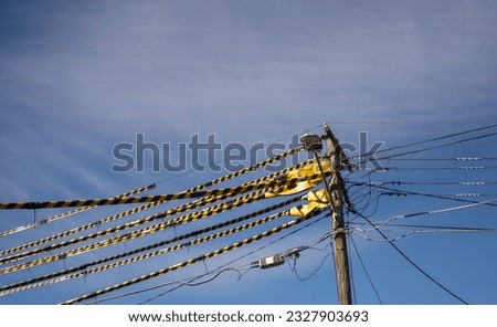 safety procedure Yellow and black striped synthetic tubes that (Tiger tails) They are clipped together over powerlines to provide a useful visual indication of live overhead powerlines. Blue sky Royalty-Free Stock Photo #2327903693