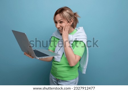 young pensive woman in casual attire working using a laptop in her hands on a blue background