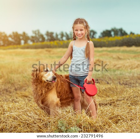 happy little girl with her dog golden retriever in rural areas in summer