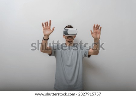 Futuristic man wearing virtual reality glasses interacts with the air in an isolated gray background.