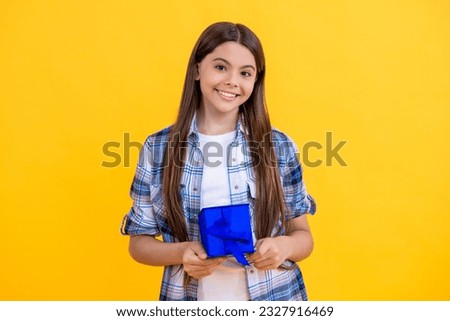 smiling teen girl holding birthday present box on background. birthday teen girl posing. teen girl with birthday gift isolated on yellow. teen girl celebrating birthday with present in studio