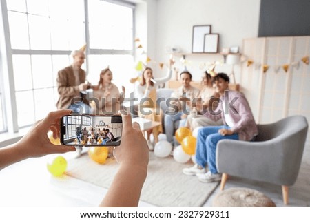 Young woman taking picture of her friends celebrating Birthday at home, closeup