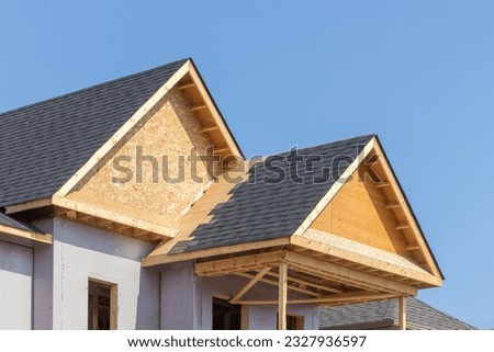 Shingle covered dormers of a residential construction project showing plywood roof and oriented strand board or chip board dormer sheathing Royalty-Free Stock Photo #2327936597