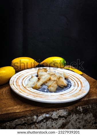 Abiu sliced fruit on porcelain plate on a dark wooden background