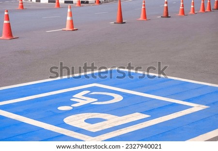 Accessible wheelchair parking sign with row of traffic cone on street surface in perspective side view