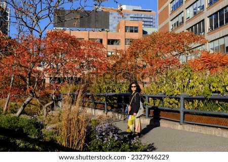 An Asian female tourist enjoy taking a picture with beautiful fall foliage at the Highland in New York City, USA.