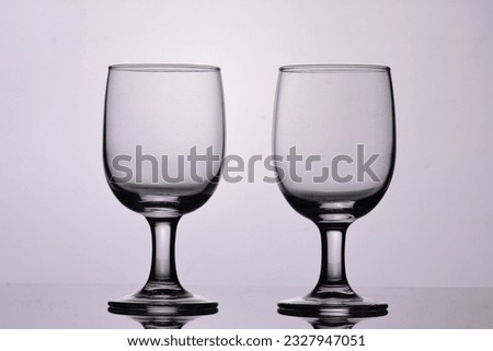 Pair of empty wine glasses pictured in a photo studio with light reflection.