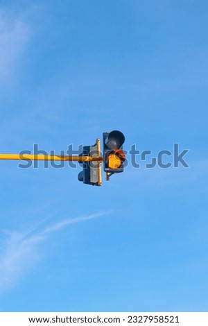 Photo of a yellow traffic sign with two lights that are on during the day