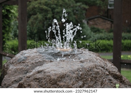 Up close picture of a in built water fountain on a rock, spraying water