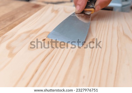 Process of puttying wooden board. Spatula, putty, wooden board. Carpentry works. Royalty-Free Stock Photo #2327976751