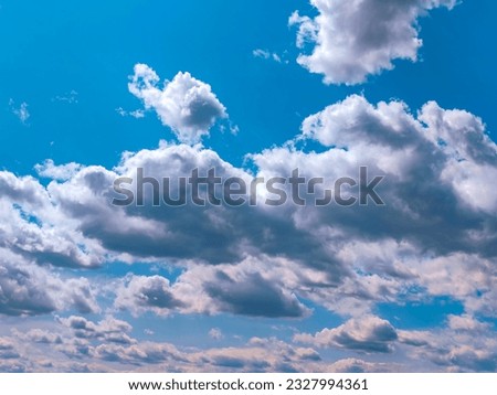 Fluffy gray and white clouds move smoothly against the blue sky.