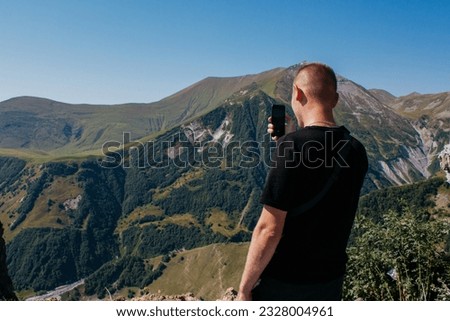 A man in the mountains takes pictures on the mountain phone