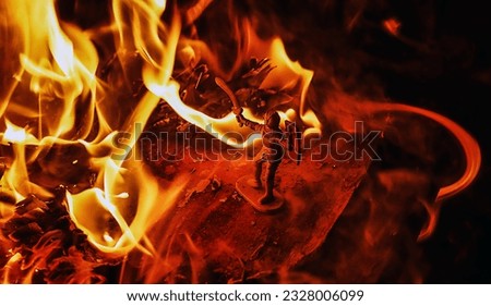 the silhouette of a miniature spartan soldier in front of fires melting