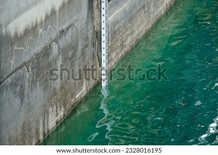 Depth marker counting surface level of sea. Vertical indicator of depth of river. Water meter. Low or high. Flood. Tide. Shortage of rain. Information bar. Global warming. Drought. Reservoir. Gauge. Royalty-Free Stock Photo #2328016195