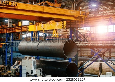 Finished pipe transportation by overhead crane in pipe factory Royalty-Free Stock Photo #2328053207