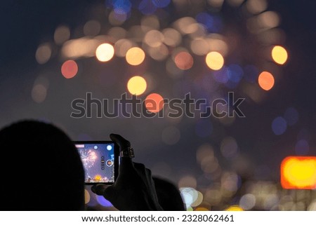 Man taking a cellphone video of fireworks on 4th of July