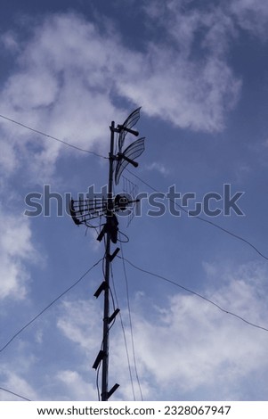 A photo of an antenna on a sunny day with clouds and a blue sky