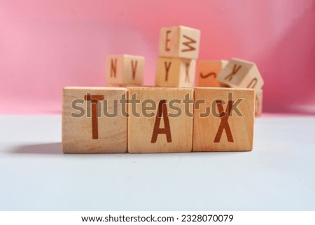 English vocabulary "TAX" with medium brown wooden blocks, pink and white background