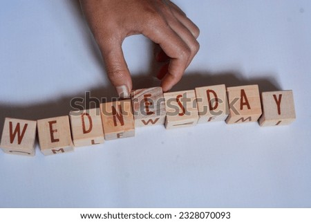 English vocabulary "WEDNESDAY" with medium brown wooden blocks, pink and white background