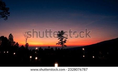 someone enjoying the reddish orange silhouettes of the morning on the Sumbing Mountains and Sindoro Temanggung