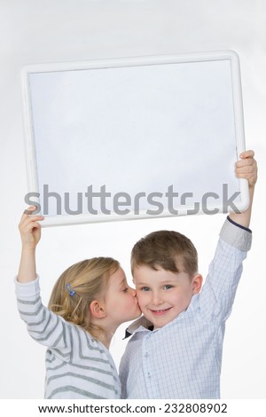 female kid kissing her friend while raising plastic panel