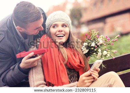 A picture of a man giving surprise gift to woman in the park