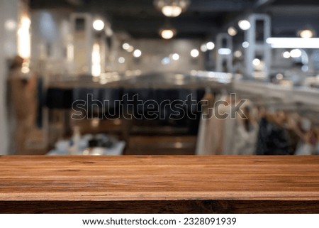 Empty wooden table space platform and blurred cloth store or fashion shop for product display montage.