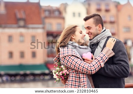 A picture of a couple on Valentine's Day in the city with flowers and heart