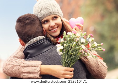 A picture of a happy woman with Valentines gift and flowers hugging her man